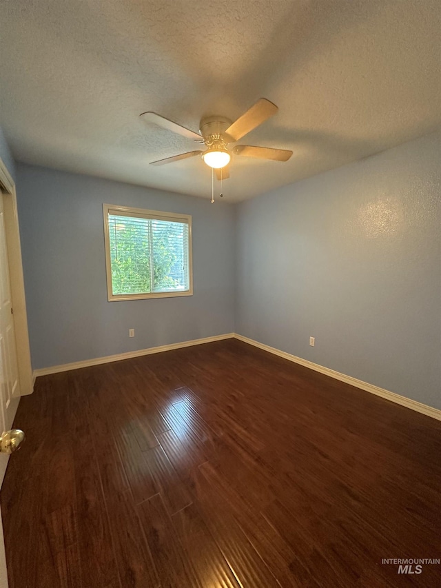 empty room featuring dark wood-type flooring, ceiling fan, and a textured ceiling