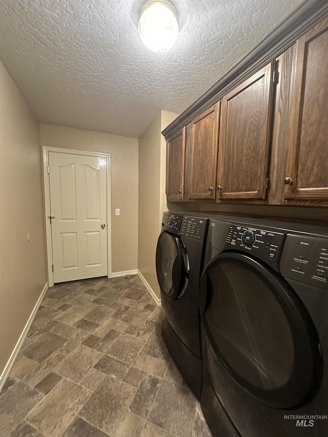 laundry area featuring cabinets, washer and clothes dryer, and a textured ceiling