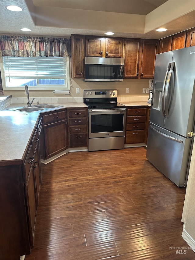 kitchen with dark brown cabinetry, stainless steel appliances, dark hardwood / wood-style flooring, and sink