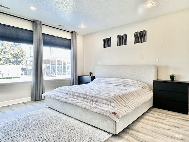 bedroom with recessed lighting, visible vents, a textured ceiling, wood finished floors, and baseboards