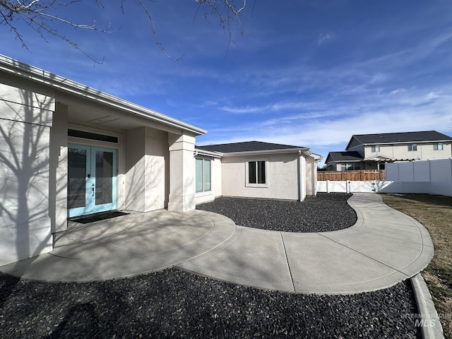 exterior space featuring stucco siding, a patio area, fence, and french doors