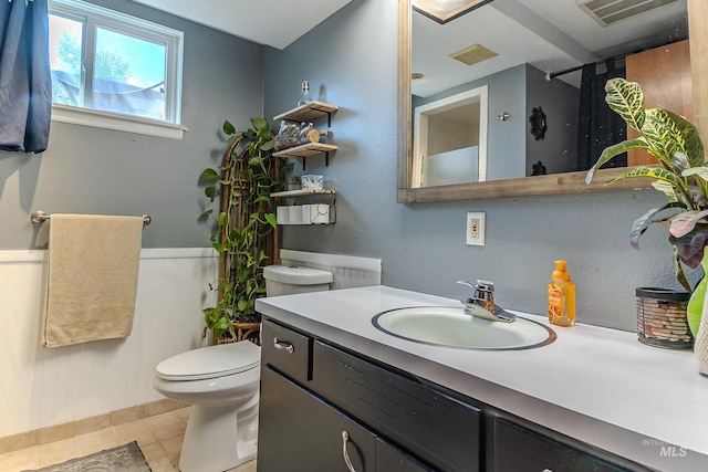 150 N 18 E, Mountain Home, ID 83647 - bathroom featuring toilet, vanity, tile patterned floors, and a wainscoted wall