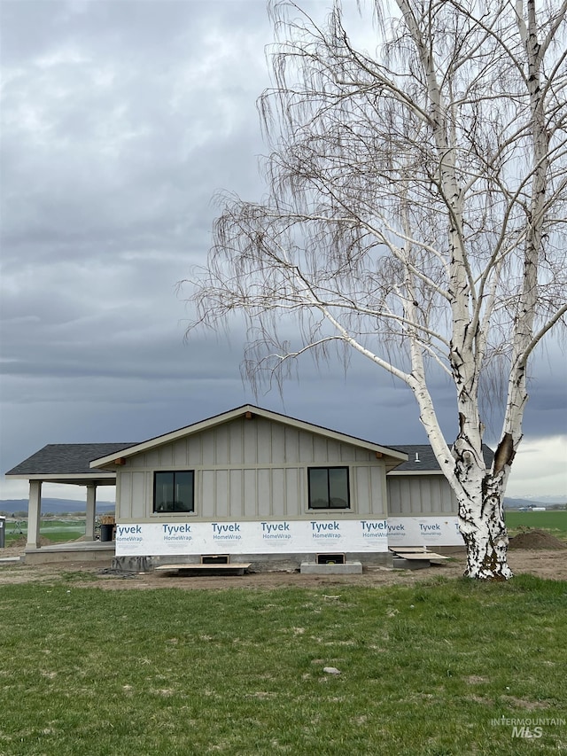 view of side of home with a lawn, board and batten siding, and roof with shingles