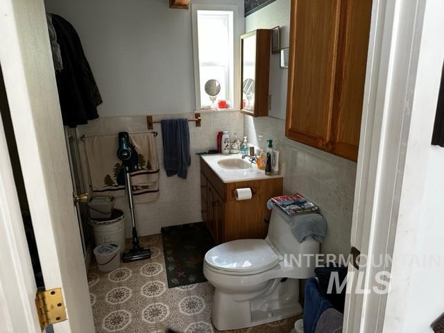 bathroom with vanity, tile walls, and toilet