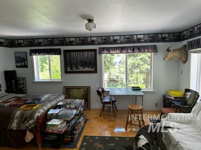 bedroom featuring multiple windows, parquet flooring, and a textured ceiling