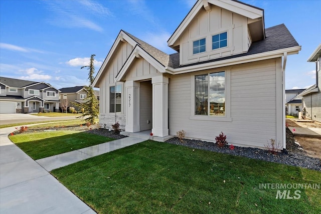 view of front facade featuring a front lawn, board and batten siding, and roof with shingles