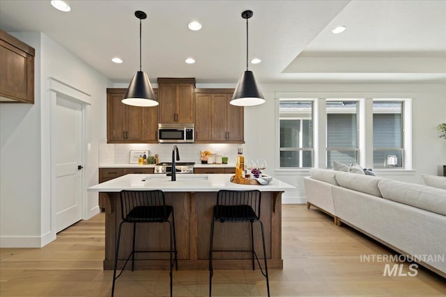 kitchen featuring stainless steel appliances, tasteful backsplash, light wood-type flooring, and light countertops