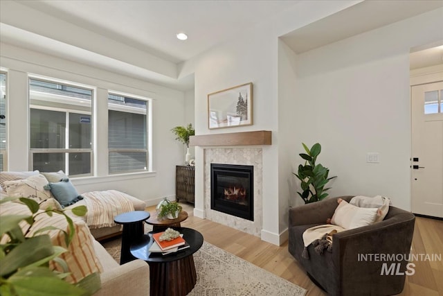 living room featuring baseboards, a premium fireplace, wood finished floors, and recessed lighting