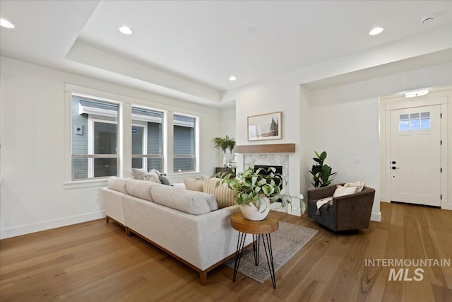 living room with recessed lighting, baseboards, wood finished floors, and a high end fireplace