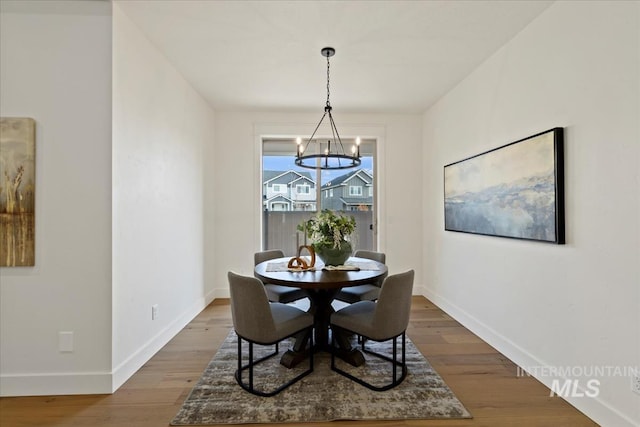 dining room with a notable chandelier, baseboards, and wood finished floors