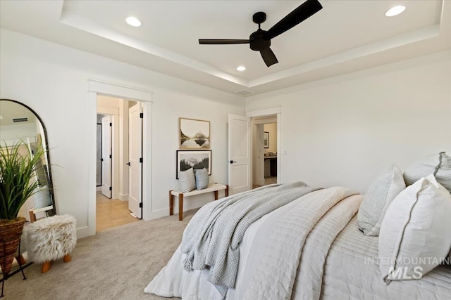 bedroom with recessed lighting, a raised ceiling, and light colored carpet