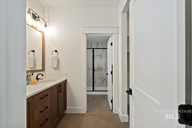 full bathroom featuring tile patterned flooring, baseboards, vanity, and a marble finish shower