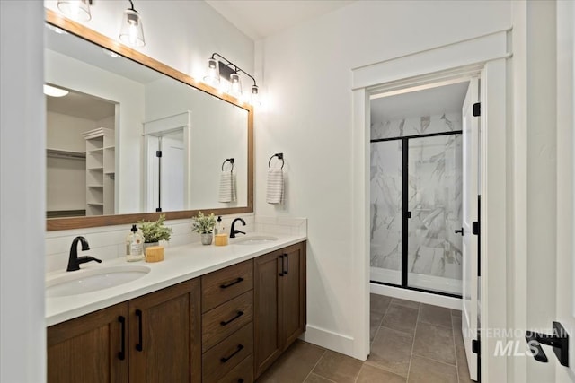 bathroom with tile patterned floors, a sink, a marble finish shower, and double vanity