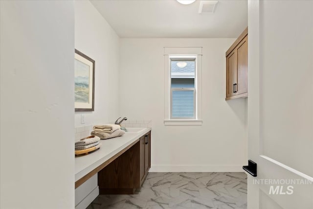 laundry room with marble finish floor, a sink, visible vents, and baseboards