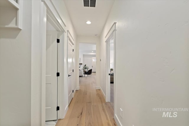 hall featuring visible vents and light wood-style flooring