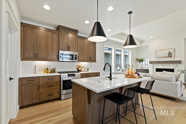 kitchen featuring a breakfast bar, light wood finished floors, light countertops, appliances with stainless steel finishes, and a sink