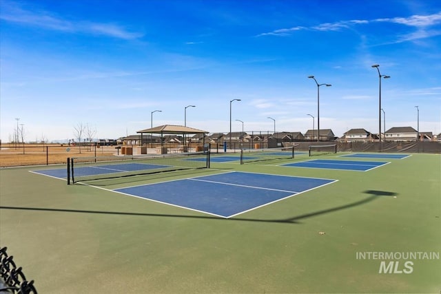 view of tennis court featuring community basketball court, fence, and a gazebo