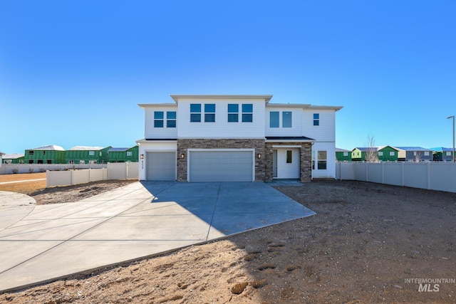 view of front of home with stone siding, driveway, a garage, and fence