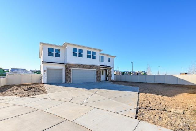 view of front of home with a garage, stone siding, driveway, and fence