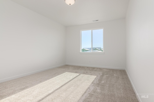 spare room with visible vents, light colored carpet, and baseboards