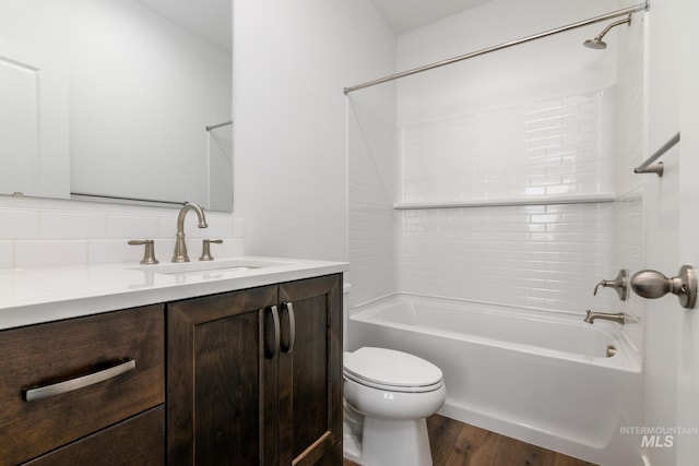 full bath with toilet, decorative backsplash, wood finished floors, shower / bath combination, and vanity