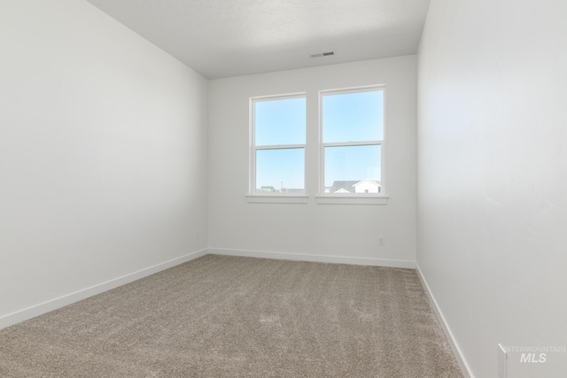 carpeted empty room featuring baseboards and visible vents