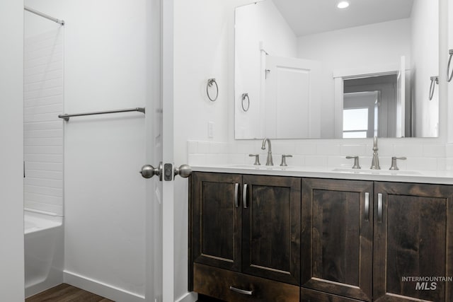 full bath featuring double vanity, tasteful backsplash, and a sink