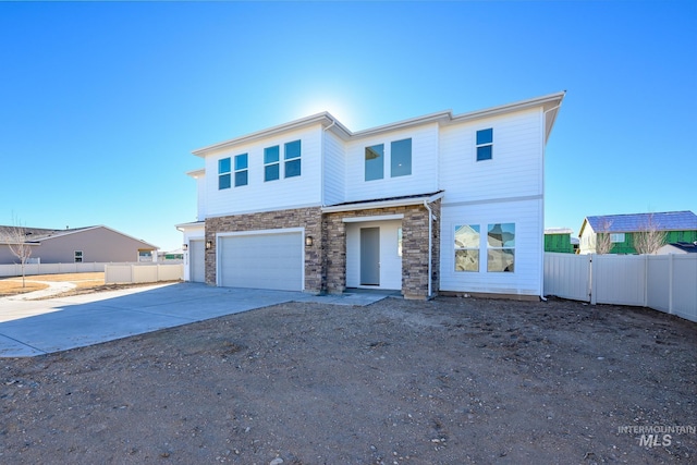 view of front of home with fence, stone siding, and driveway