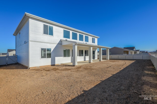 rear view of property featuring a patio area, a gate, and a fenced backyard