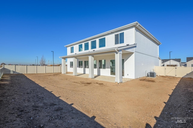 rear view of property featuring central AC unit, a patio, a fenced backyard, and a gate