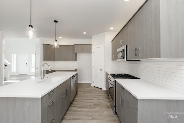 8592 N Ferris Ave, Boise, ID 83714 - kitchen featuring stainless steel appliances, a sink, tasteful backsplash, light wood-type flooring, and light countertops