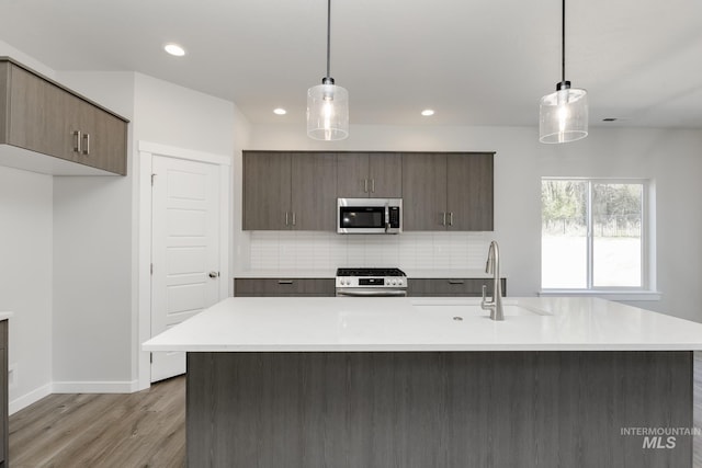 8592 N Ferris Ave, Boise, ID 83714 - kitchen with stainless steel appliances, a sink, light countertops, decorative backsplash, and light wood-type flooring