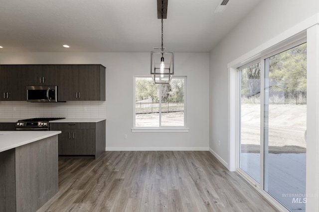 8592 N Ferris Ave, Boise, ID 83714 - kitchen featuring stainless steel microwave, black stove, light countertops, backsplash, and light wood finished floors