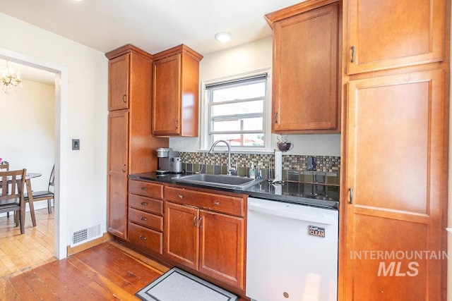 702 S Opal St, Boise, ID 83705 - kitchen featuring white dishwasher, a sink, dark countertops, dark wood finished floors, and decorative backsplash