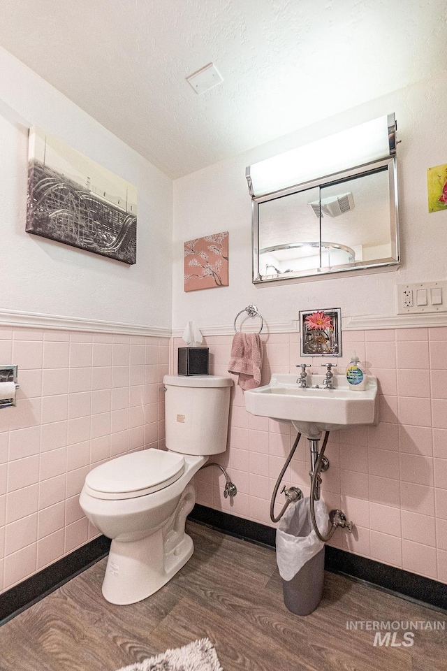 702 S Opal St, Boise, ID 83705 - half bathroom featuring tile walls, wood finished floors, toilet, and a wainscoted wall
