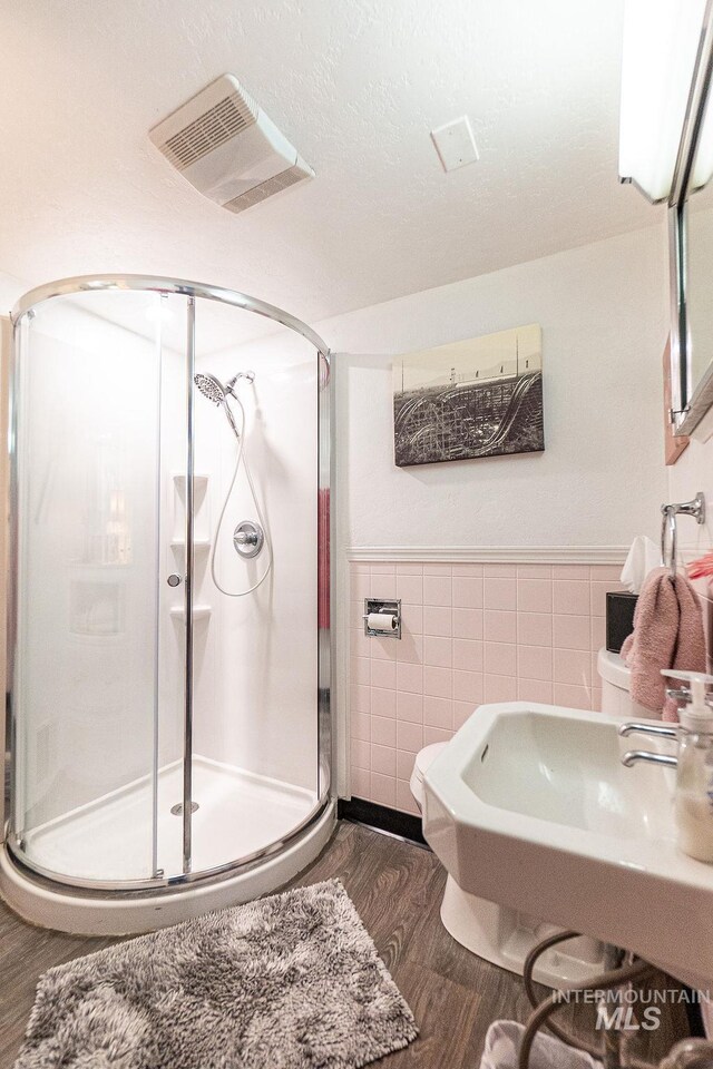 702 S Opal St, Boise, ID 83705 - bathroom featuring tile walls, a shower stall, wood finished floors, and wainscoting