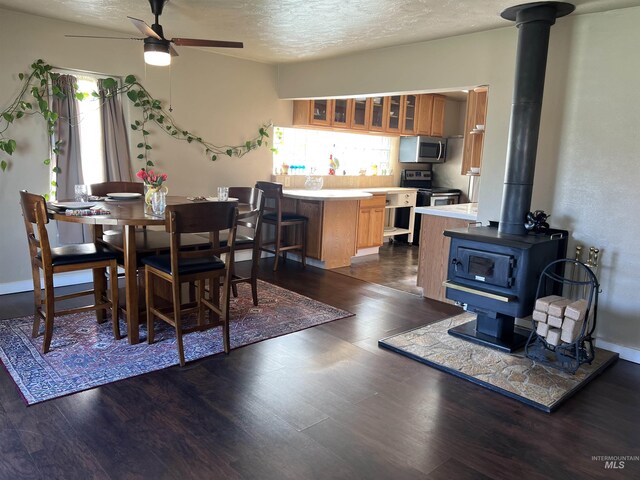 140 3rd St, Grand View, ID 83624 - dining space featuring a wood stove, a textured ceiling, a ceiling fan, and dark wood finished floors