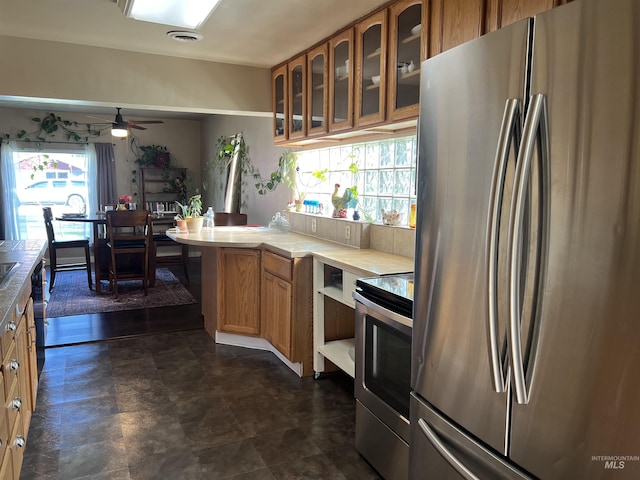 140 3rd St, Grand View, ID 83624 - kitchen with glass insert cabinets, light countertops, a ceiling fan, brown cabinetry, and appliances with stainless steel finishes