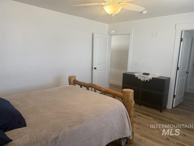 bedroom with a textured ceiling, a ceiling fan, and wood finished floors