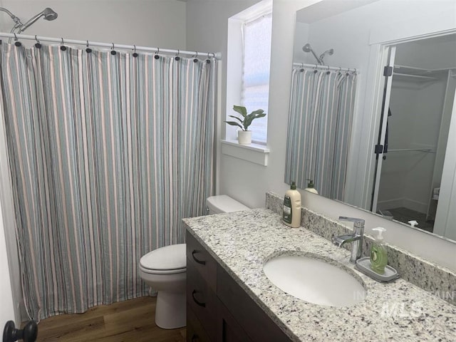 bathroom with a shower with shower curtain, toilet, wood finished floors, and vanity