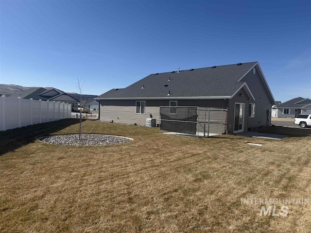 rear view of property featuring a yard and fence