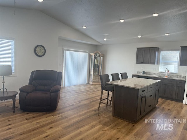 kitchen featuring a kitchen bar, lofted ceiling, a kitchen island, and wood finished floors