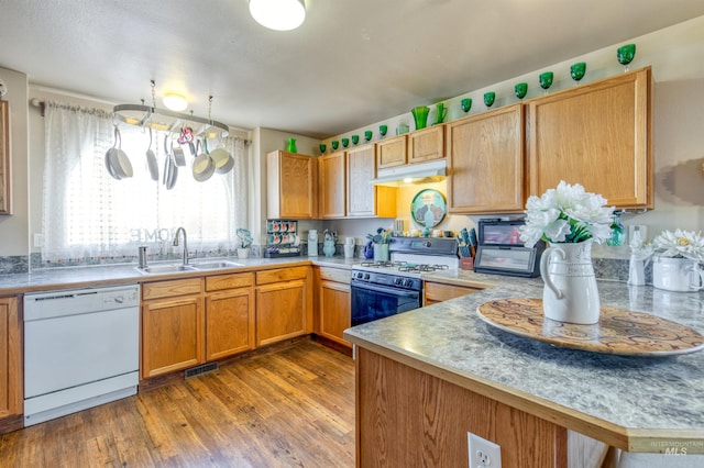 kitchen with light countertops, light wood-style flooring, a sink, white appliances, and a peninsula