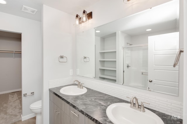 bathroom featuring vanity, toilet, a shower with door, and backsplash