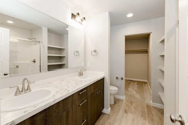 bathroom with built in shelves, vanity, hardwood / wood-style flooring, toilet, and a shower with shower door