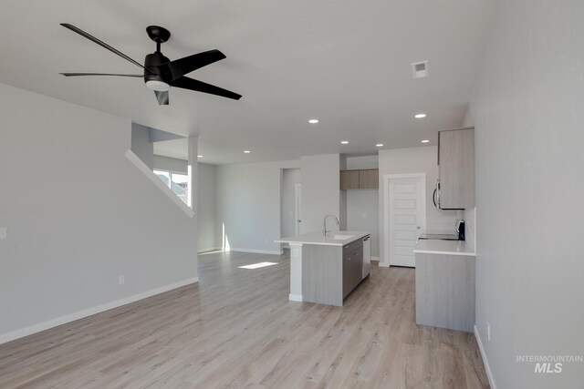 kitchen featuring light brown cabinets, a kitchen island with sink, ceiling fan, light wood-type flooring, and range