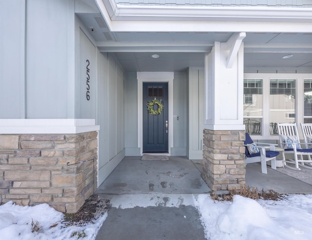 view of exterior entry with a porch and stone siding