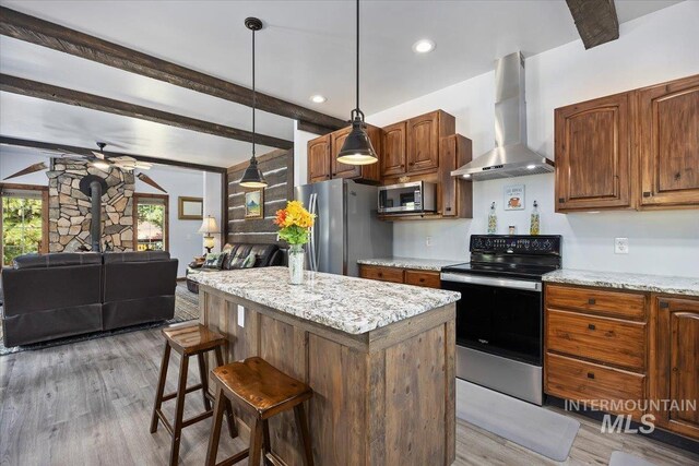 1010 N Hidden Pine Rd, Pine, ID 83647 - kitchen featuring wall chimney exhaust hood, appliances with stainless steel finishes, open floor plan, wood finished floors, and beam ceiling