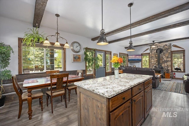 1010 N Hidden Pine Rd, Pine, ID 83647 - kitchen featuring a wood stove, wood finished floors, beamed ceiling, a ceiling fan, and hanging light fixtures