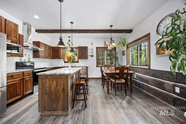 1010 N Hidden Pine Rd, Pine, ID 83647 - kitchen with stainless steel appliances, wall chimney range hood, light wood-style flooring, a breakfast bar area, and a kitchen island